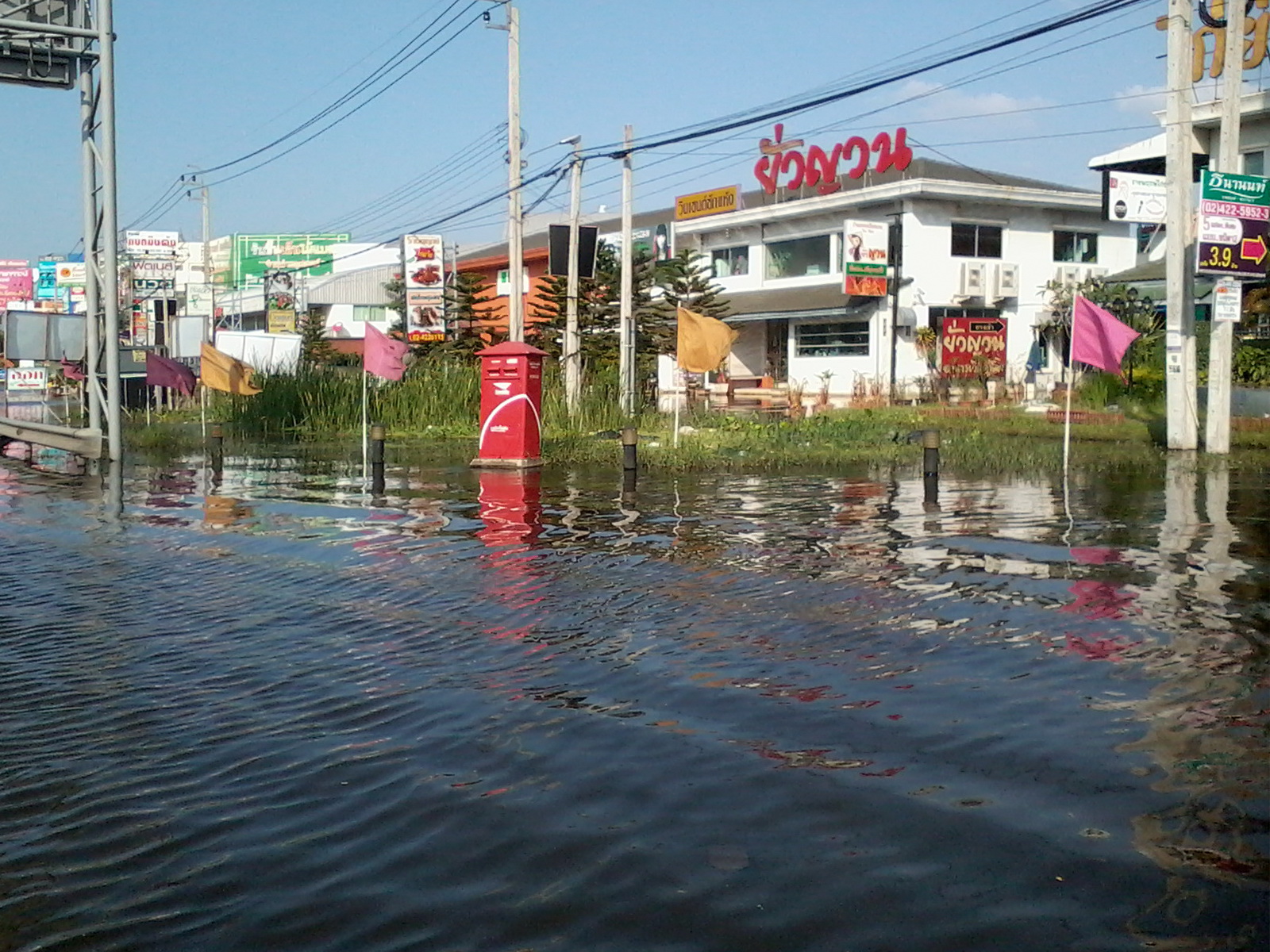 Flooded residential street in Nonthaburi near Bangkok, Thailand, with water covering the road outside homes: a reminder for anyone living in Thailand to check flood insurance.