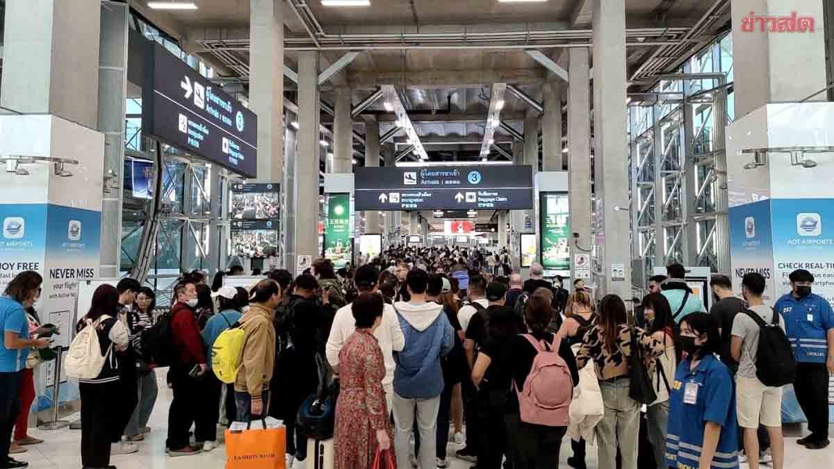 Travellers queuing in the arrivals hall at a Thai international airport.